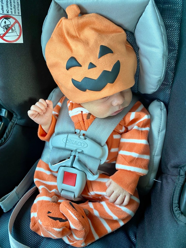 Baby in a orange, white and black pumpkin hat and onesie